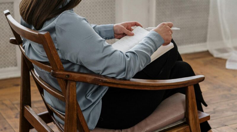 Suaugęs žmogus rašo asmeninį dienoraštį jaukiame kambaryje.