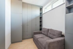 Jauki ir funkcionali svetainė su minkšta sofa-lova, moderniais baldais, lentynomis daiktams bei šiltu apšvietimu, sukurta ribotoje erdvėje.